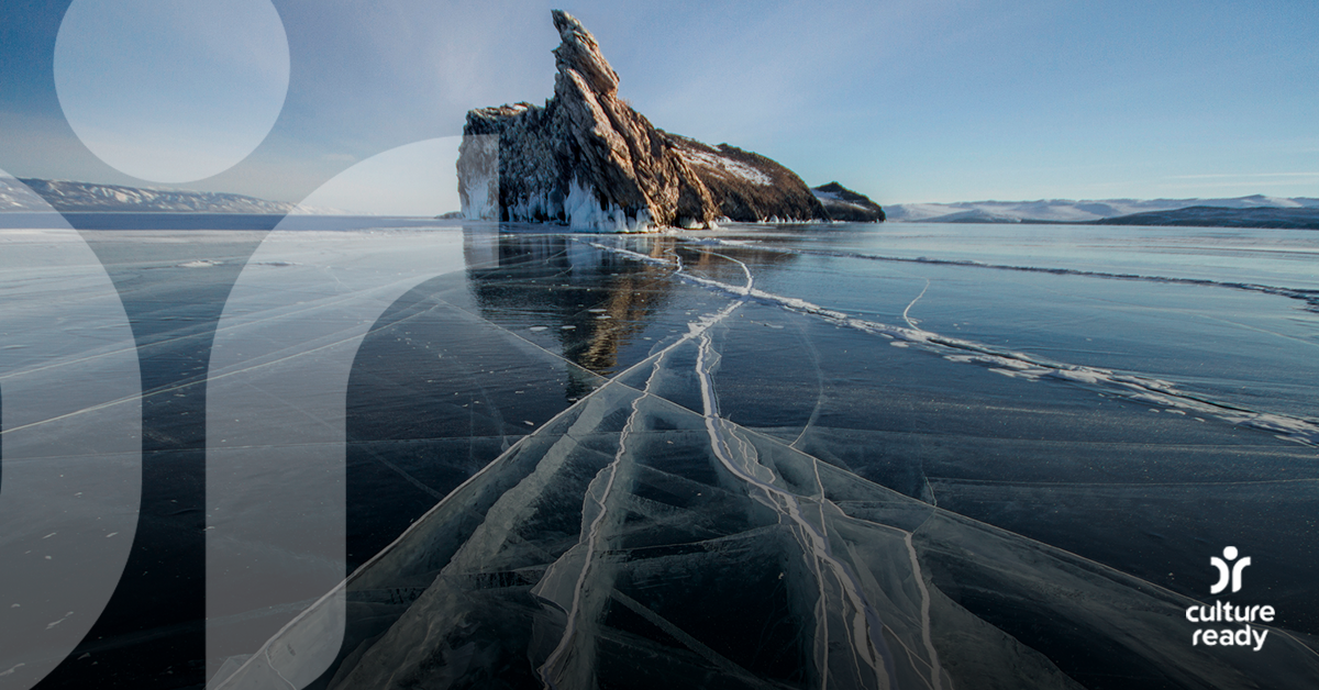 A landscape of Lake Biakal with a blue sky, frozen dark blue ice and a large rock jetting out of the frozen lake
