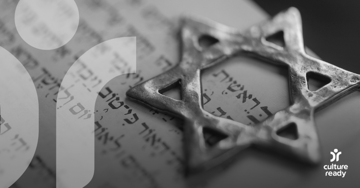 A silver star of David sits atop a page of Hebrew text, the photo is in black and white