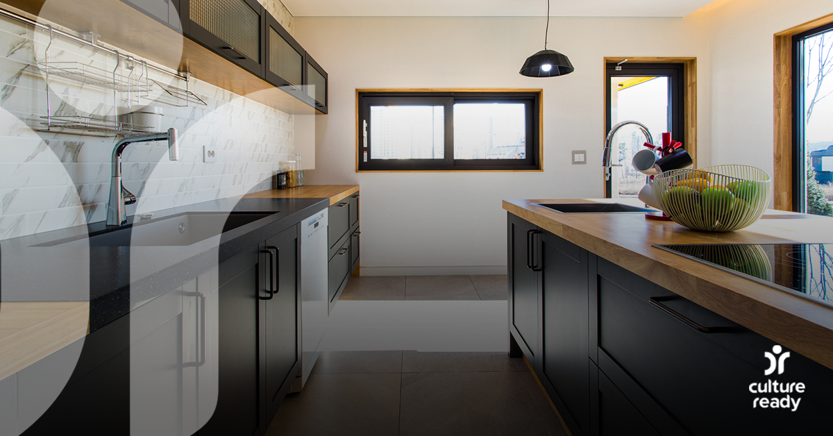 A modern kitchen with white walls, dark cabinets and wood counter tops with one window