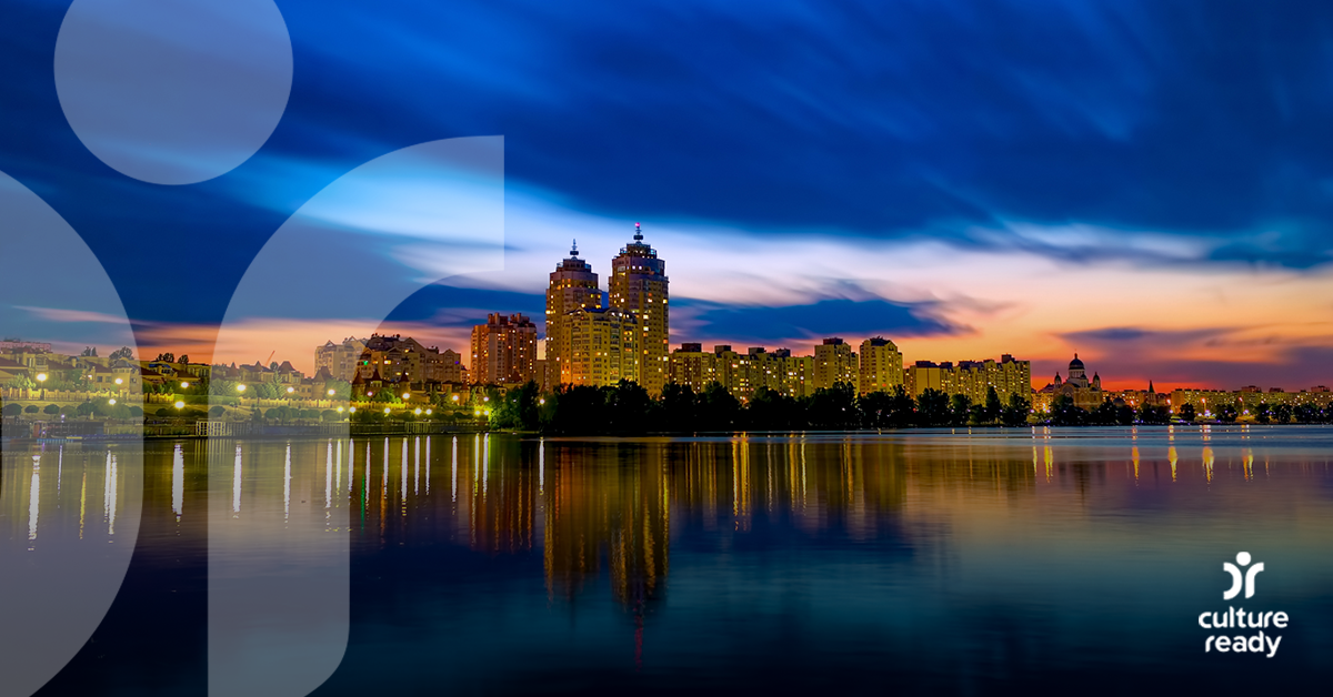 A sun sets over a city, the sky and water are both deep blue and the city is up lit in a way that gives it a golden hue