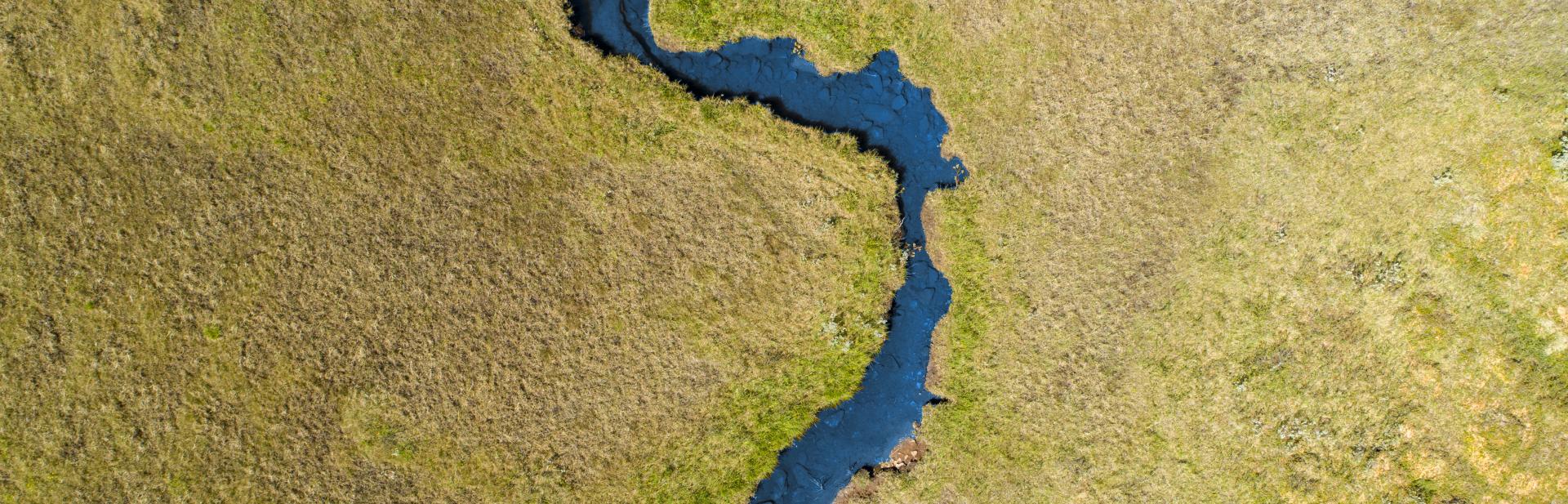 Aerial view of river winding through grasslands.