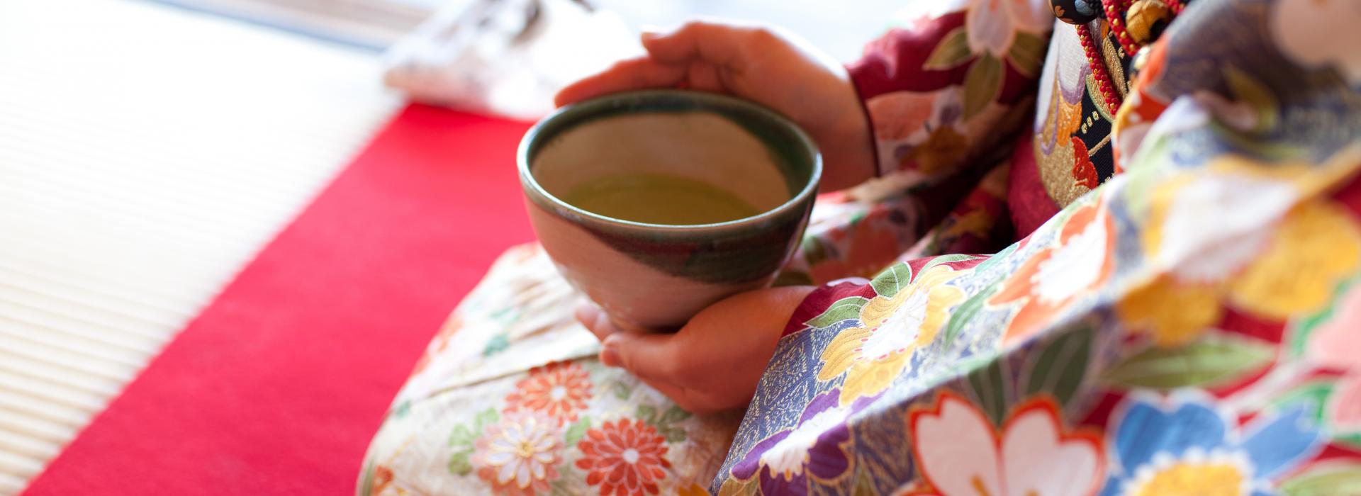 Woman in kimono holding mug of tea.